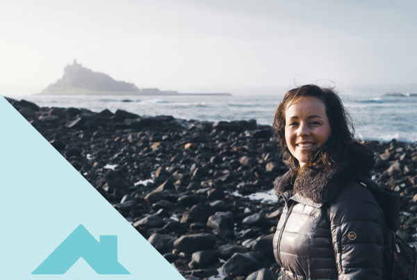 A lady on the beach at Marion with St Michael's Mount in the background and the Supportive Stays logo with a house above it.